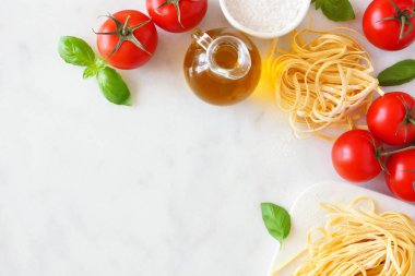 Taze Linguine, domates, zeytinyağı ve fesleğen dahil Makarna malzemeleri. Yukarıdaki görünüm, beyaz mermer arka plana karşı köşe sınırı. Boşluk Kopyala.