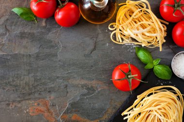 Taze Linguine, domates, zeytinyağı ve fesleğen dahil Makarna malzemeleri. Yukarıdaki görünüm, bir arduvaz arka planda köşe kenarlık. Boşluk Kopyala.