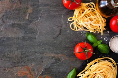 Taze Linguine, domates, zeytinyağı ve fesleğen dahil Makarna malzemeleri. Yukarıdaki görünüm, bir arduvaz arka plan karşı yan sınır. Boşluk Kopyala.