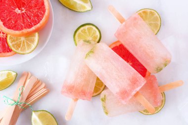 Bir tabakta kireç ve greyfurt buzlu şekerler, beyaz mermer arka plan karşı üst görünüm masa sahnesi