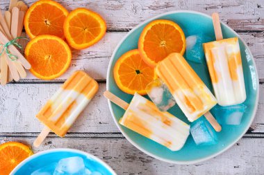 Turuncu yoğurt mavi bir tabak ta popsicles, beyaz ahşap arka plan karşı üst görünüm masa sahnesi