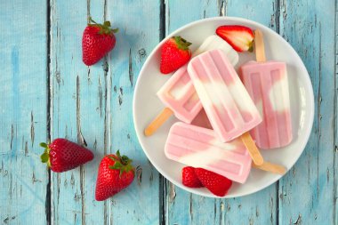 Bir tabak ta sağlıklı çilek yoğurt yaz popsicles, mavi ahşap arka plan karşı üst görünüm masa sahnesi
