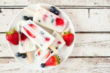 Sağlıklı çilek yaban mersini yoğurt buz bir tabak üzerinde açılır, beyaz ahşap arka plan karşı üst görünümü