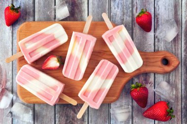 Bir servis tahtası üzerinde Sağlıklı çilek yoğurt yaz popsicles, rustik ahşap arka plan karşı üst görünüm masa sahnesi