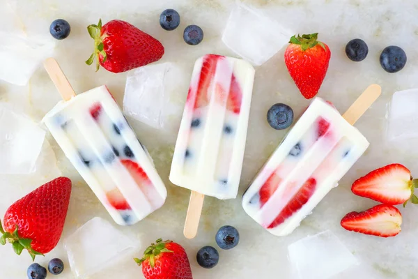 Sağlıklı çilek yaban mersini yoğurt buz pops, beyaz mermer arka plan üzerinde görünümü yukarıda