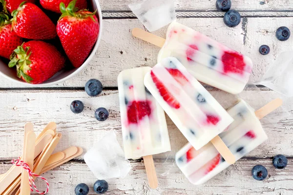 Sağlıklı çilek yaban mersini yoğurt popsicles, beyaz ahşap arka plan karşı üst görünüm yaz masa sahnesi