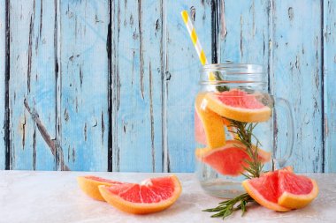 Greyfurt ve biberiye bir mason kavanoz cam detoks suyu aşıladı. Rustik mavi ahşap arka plan karşı Yaz içki.