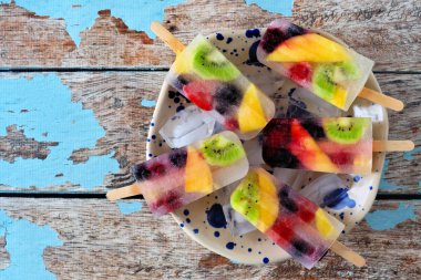 Sağlıklı karışık meyve yaz buz pops. Rustik mavi ahşap arka plan karşı kase üst görünümü.