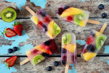 Sağlıklı karışık meyve yaz popsicles. Yukarıda rustik mavi ahşap arka plan üzerinde dağınık görünümü.
