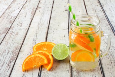 Turuncu ve kireç rustik beyaz ahşap arka plan karşı bir mason kavanoz cam detoks su aşılanmış