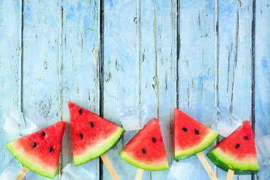 Alt sınır oluşturan rustik mavi ahşap arka planda karpuz dilim Popsicles