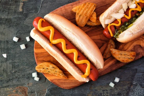 Hot Dogs Mit Garnierungen Und Kartoffelkeilen Auf Holzbrett Nahaufnahme Draufsicht — Stockfoto