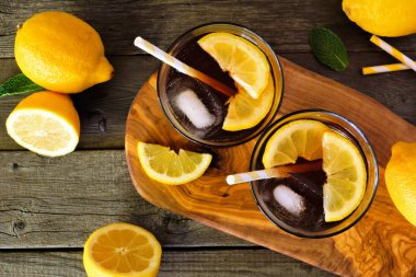 Yaz buzlu çay, ahşap servis tahtasında iki bardak. Rustik koyu ahşap arka plan üzerinde üst görünüm masa sahnesi.