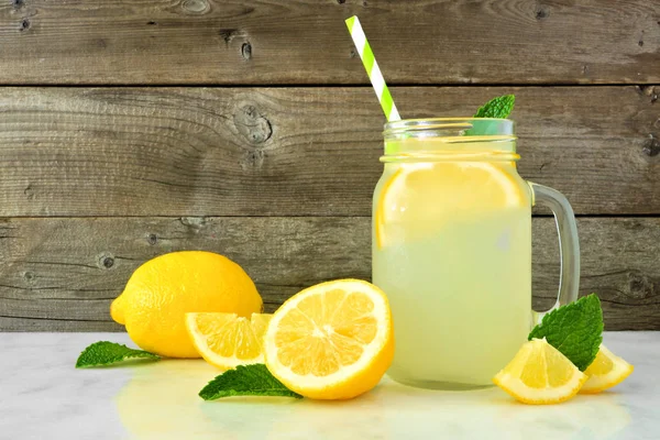 Limonlu bir kavanoz camında ev yapımı limonata. Rustik ahşap arka planda yan görünüm.