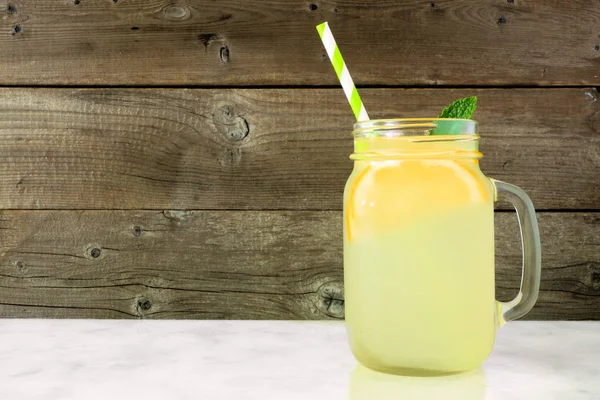 Homemade lemonade in a mason jar glass. Side view on a rustic wood background.
