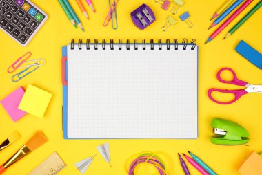 Okul malzemeleri çerçeveli boş grafik kağıt defter sarı bir arka plan. Okul konseptine geri dönelim. Kopyalama alanı.