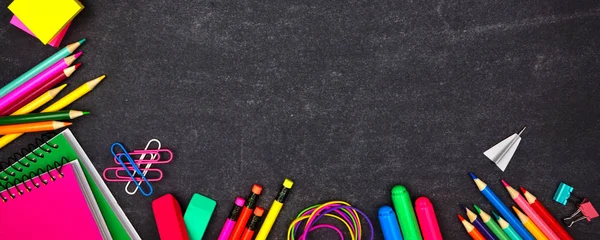 School supplies corner border banner. Overhead view on a chalkboard background with copy space. Back to school concept.