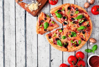 Pepperoni, mantar, yeşil biber, zeytin, soğan ve fesleğen ile ev yapımı pizza. Üst görünüm, kopya alanı ile beyaz ahşap arka plan karşı köşe kenarlık.