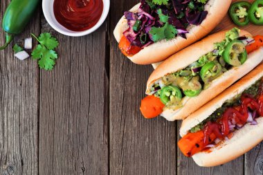 Çeşitli topingler ile Havuç sosisli sandviç. Rustik ahşap arka plan üzerinde köşe sınırı. Sağlıklı bitki bazlı etsiz yemek konsepti.