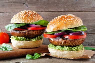 Koyu ahşap arka plan karşı avokado, domates, ıspanak ve soğan ile Portobello mantar etsiz burger