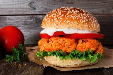 Buffalo soslu karnabahar burger karanlık bir arka plan aleyhine kapatın. Sağlıklı beslenme, bitki bazlı et ikame konsepti.