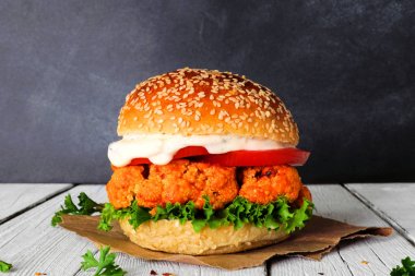 Koyu bir arka plan karşı buffalo soslu karnabahar burger. Sağlıklı beslenme, bitki bazlı et ikame konsepti.