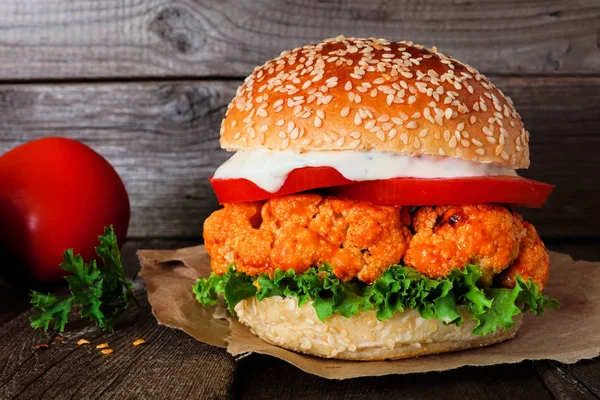 Buffalo soslu karnabahar burger karanlık bir arka plan aleyhine kapatın. Sağlıklı beslenme, bitki bazlı et ikame konsepti.