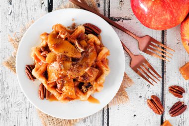 Fırında elma, pekan ve karamel ile tatlı kahvaltı waffle. Beyaz ahşap arka plan üzerinde üst görünümü. Sonbahar gıda teması.