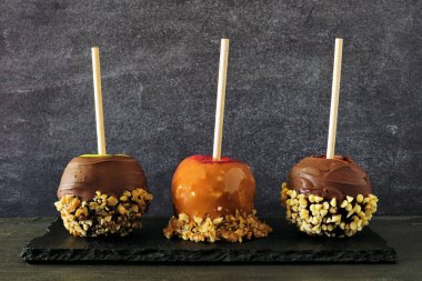 Karamel, çikolata ve fındık ile sonbahar şeker elma üç tür, bir kayrak arka plan karşı yan görünüm