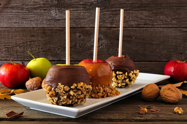 Plate of fall candy apples with chocolate and caramel against a dark wood background