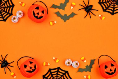 Dağınık şeker ve dekor Cadılar Bayramı çift sınır. Turuncu bir arka plan üzerine kopya alanı ile düz yatıyordu.