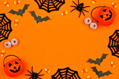 Dağınık şeker ve dekor Halloween çerçeve. Turuncu bir arka plan üzerine kopya alanı ile düz yatıyordu.
