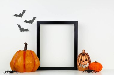 Bir raf veya masada Jack o Lantern ve kabak dekor ile siyah çerçeve kadar mock. Cadılar Bayramı konsepti. Yarasalarla beyaz bir duvara karşı portre çerçevesi.