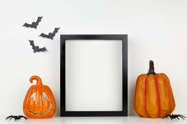 Bir raf veya masada Jack o Lantern ve kabak dekor ile siyah çerçeve kadar mock. Cadılar Bayramı konsepti. Yarasalarla beyaz bir duvara karşı portre çerçevesi.