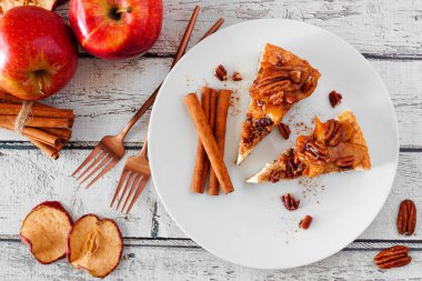 İki dilim karamel elmalı cevizli cheesecake. Beyaz ahşap arka plan ile üst görünüm masa sahnesi. Sonbahar tatlısı.