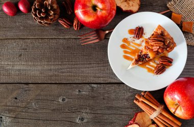 Dilim karamel elma cevizli cheesecake. Rustik ahşap arka plan ile üst görünüm köşe sınırı. Sonbahar tatlısı.