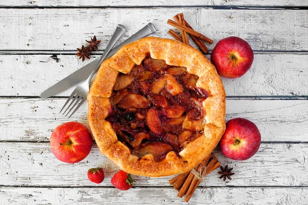 Apple strawberry pie, top view on a rustic white wood background with frame of ingredients. Autumn food concept.