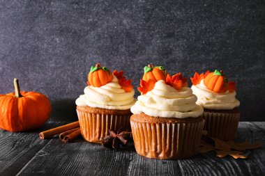 Kremsi frosting ve sonbahar topingler ile Sonbahar kabak baharat cupcakes. Koyu arka plana karşı yan görünüm sahnesi.