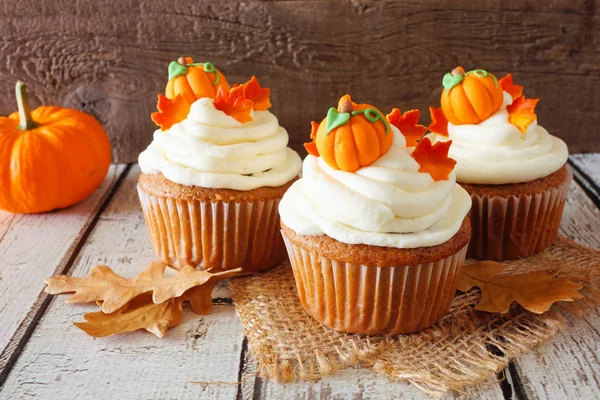 Kremsi frosting ve sonbahar topingler ile Sonbahar kabak baharat cupcakes. Rustik ahşap arka plana yakın.