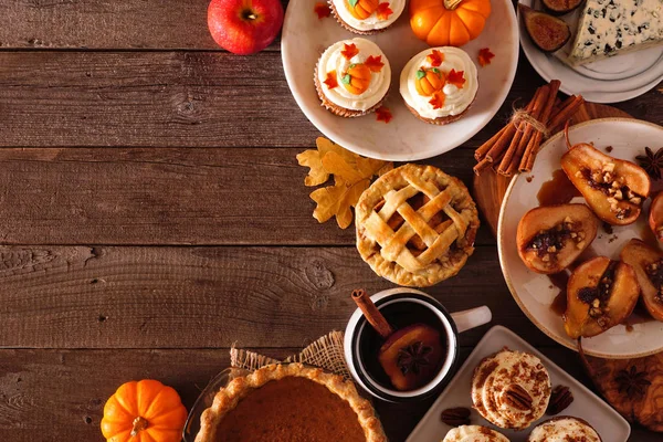 Autumn food corner border. Table scene with a selection of pies, appetizers and desserts. Top view over a rustic wood background. Copy space.