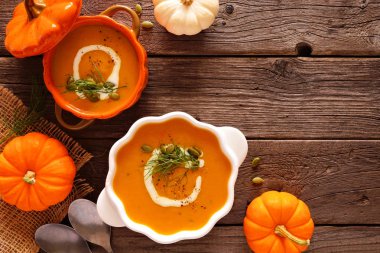 İki kabak kasesinde ev yapımı kabak çorbası. Sonbahar gıda konsepti. Kopya alanı ile rustik ahşap arka plan üzerinde üst görünüm köşe kenarlığı.