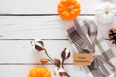 Gümüş takımlı Şükran Günü etiketiniz kutlu olsun. Parmak izi peçetesi, balkabağı ve dekoru kontrol edin. Beyaz ahşap arka plana karşı üst görünüm kenarı.