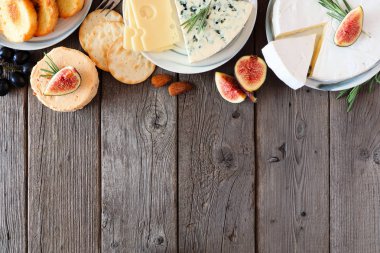 Peynir, ekmek, kraker ve incir seçimi. Kopya alanı ile kırsal ahşap arkaplan üzerindeki en üst görünüm sınırı.