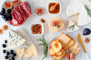 Çeşitli peynirler ve meze mezeleri. Beyaz mermer bir arka planda, masa manzarasının üstünde.