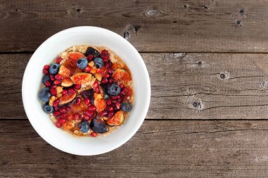 İncirli yulaf ezmesi, yaban mersini, nar ve tatlı jöle. Ahşap arka planda üst manzara. Gıda konsepti.