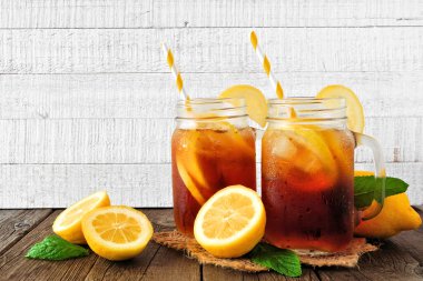 Mason kavanozlarında soğuk yaz buzlu çayı. Parlak beyaz ahşap arka plana karşı yan görünüm.