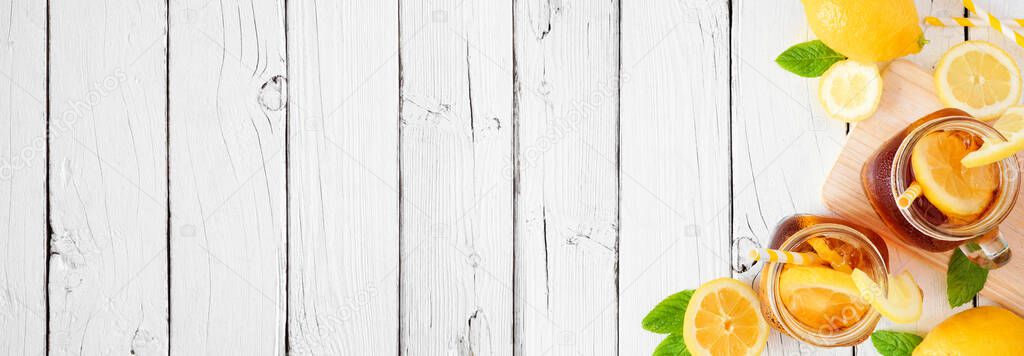 Cool summer iced tea corner border. Above view with copy space on a rustic white wood banner background.