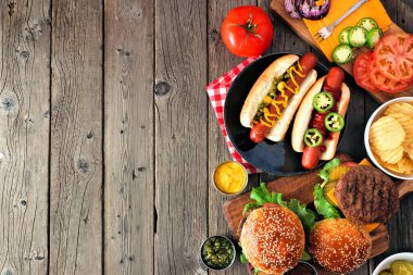 Sosisli ve hamburger büfesiyle yaz barbekü ve yiyecek sınırı. Koyu renk ahşap bir arka plan. Boşluğu kopyala.