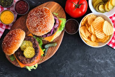 Patates cipsli barbekü hamburgeri. Koyu bir arkaplan üzerinde üst görünüm tablo sahnesi.