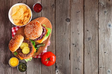 Servis panosunda barbekü hamburgerleri. Koyu ahşap bir arkaplanda, kopya alanı olan masa manzarasının üstünde.